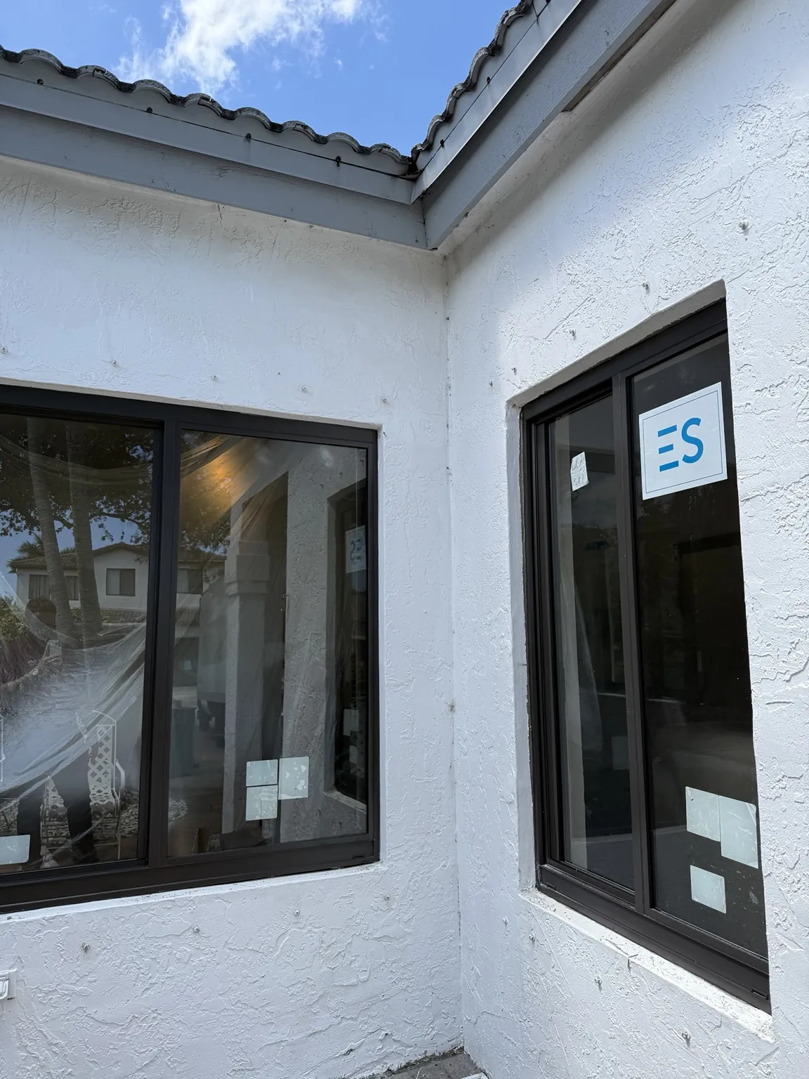Completed black-framed impact windows on a stucco corner